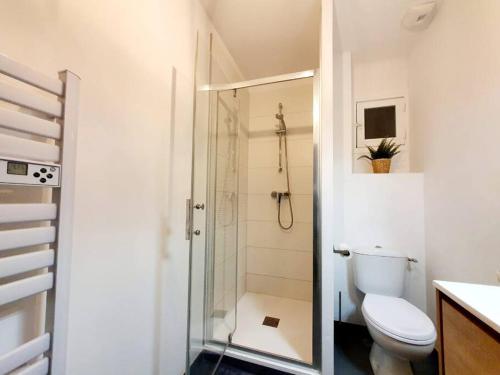 a white bathroom with a shower and a toilet at Le Cosy Paradis par Madame Conciergerie in Bruz