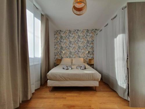 a bedroom with a bed with two pillows on it at Le Cosy Paradis par Madame Conciergerie in Bruz