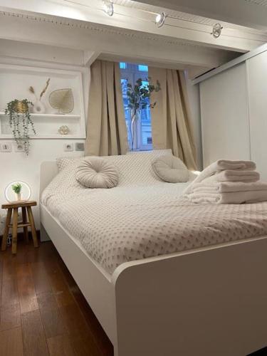 un lit blanc dans une chambre avec une fenêtre dans l'établissement Le Central - Parking Privé, à Douai