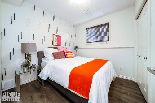 a bedroom with a bed with an orange and white blanket at Chic Modern Vibes - Sleeps 6 - Netfix - Wifi - Long Stays in Edmonton