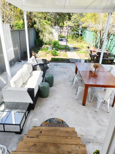 a patio with a couch and tables and an umbrella at Stylish Queen Room 1Min Walk to Station 5Min to City 10Min to Airport in Sydney