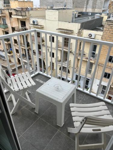 - Balcón con mesa blanca y 2 sillas en Sunquest court, en St Paul's Bay