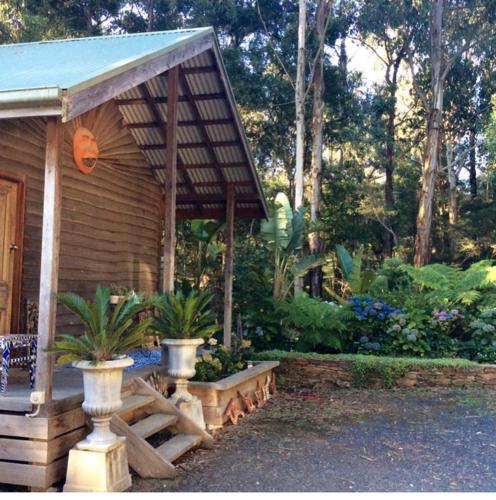 a small wooden cabin with a porch and plants at Rainy Hill Retreat - The Cottage in Cockatoo