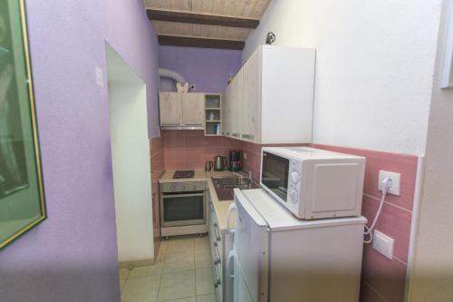 ボルにあるApartments La Perlaの紫の壁のキッチン、冷蔵庫(電子レンジ付)