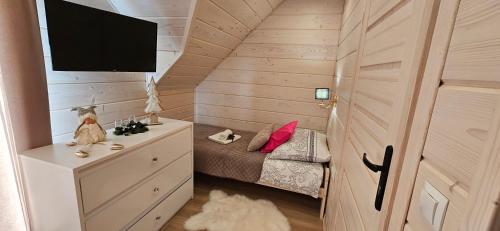 a small room with a bed and a tv at Bieszczadzkie Chaty in Polańczyk