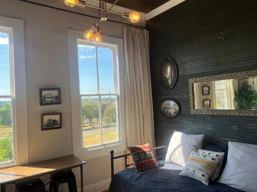 a bedroom with a bed and a table and windows at Masseys on Grove Unit B in Vicksburg