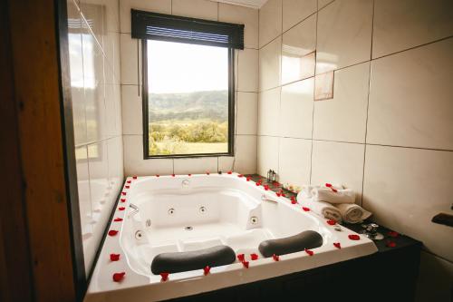 y baño con bañera y ventana. en CHALE SOL NASCENTE en Urubici