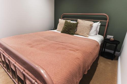ein Bett mit einer orangefarbenen Decke und Kissen darauf in der Unterkunft Wych Cottage, Striking 2 Bed, Parking, King Bed, First Floor Flat in Somerton