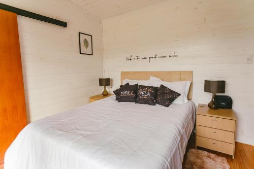 1 dormitorio con 1 cama con sábanas y almohadas blancas en CHALE SOL NASCENTE en Urubici