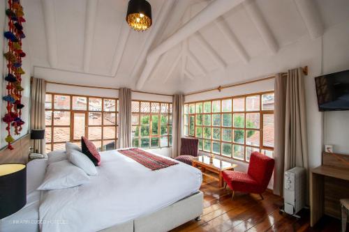 1 dormitorio con 1 cama blanca grande y ventanas en Inkarri Cusco, en Cusco