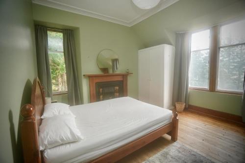 a bedroom with a bed with white sheets and a fireplace at Ardchoile, Cairngorms - Escape Cottages Scotland in Kingussie