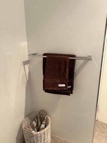a towel rack with towels and a basket in a bathroom at Whitfords Delight Bed & Breakfast in Perth