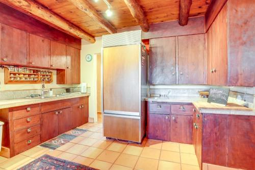 a kitchen with wooden cabinets and a stainless steel refrigerator at Peaceful Historic Cottage on Sedona Wine Trail in Cottonwood