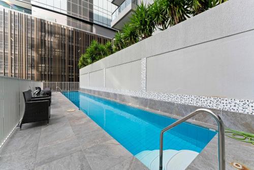 uma piscina com uma cadeira ao lado de um edifício em Vida Central - 2 bed, 1.5 bath w parking, gym & pool em Newcastle