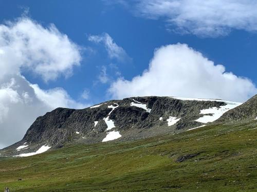 a mountain with snow on top of a green hill at Bjørnebuhytten, Geilo, 13 sengeplasser med privat Jacuzzi og el-bil-lading in Geilo