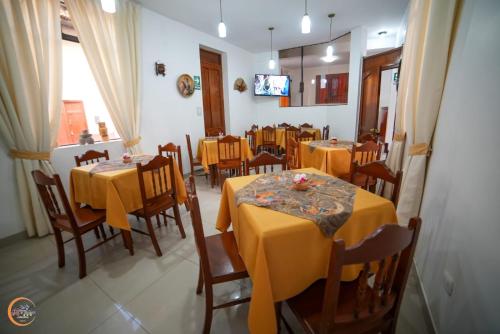 uma sala de jantar com mesas e cadeiras amarelas e uma televisão em El Cumbe Inn em Cajamarca