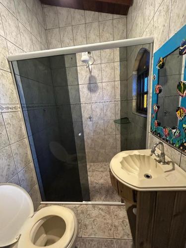 a bathroom with a shower and a toilet and a sink at pousada coruja maresias in São Sebastião