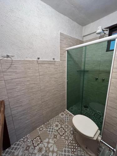 a bathroom with a toilet and a glass shower at pousada coruja maresias in São Sebastião