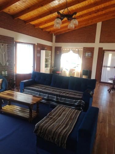 una sala de estar con sofás azules y techo de madera. en La Casa de Thelma en El Corcovado
