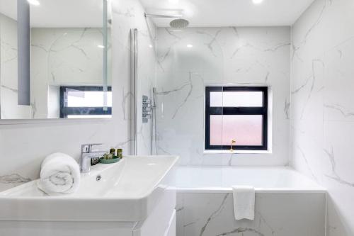 een witte badkamer met een wastafel en een spiegel bij 4bed large modern near elizabeth line west london flat free parking in Londen