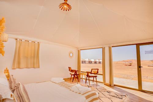 Schlafzimmer mit einem Bett, einem Tisch und Stühlen in der Unterkunft Sahara Royal Resort in Merzouga