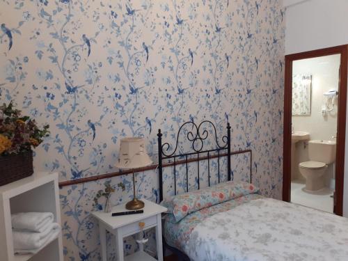 um quarto com uma cama com papel de parede azul e branco em Uría 25 rooms em Oviedo