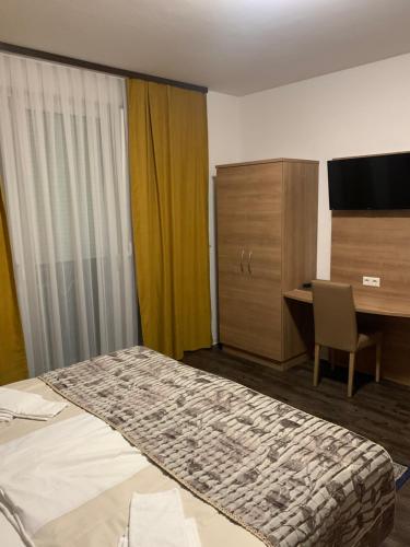 a hotel room with a bed and a desk and a television at Hotel Pizzeria Da Beni in Kochersteinsfeld