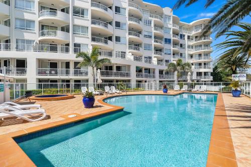 a swimming pool in front of a large apartment building at Kirra Beach Apartments in Gold Coast