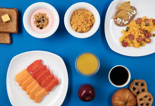 a blue table with plates of breakfast food on it at One Queretaro Aeropuerto in Querétaro