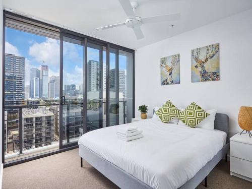 a bedroom with a white bed and a large window at Artistic South Brisbane 2 bedroom Apartment with Parking in Brisbane