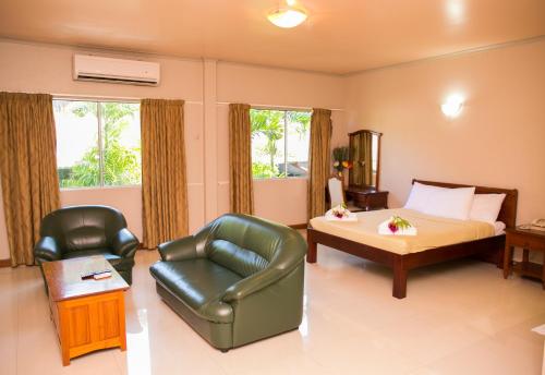 a bedroom with a bed and a chair and a couch at Hideaway Hotel in Port Moresby