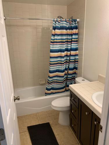 a bathroom with a tub and a toilet and a shower curtain at West Wing in San Jose