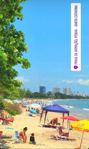 a beach with people laying on the sand and umbrellas at Chalés do Parque Hospedagem in Penha