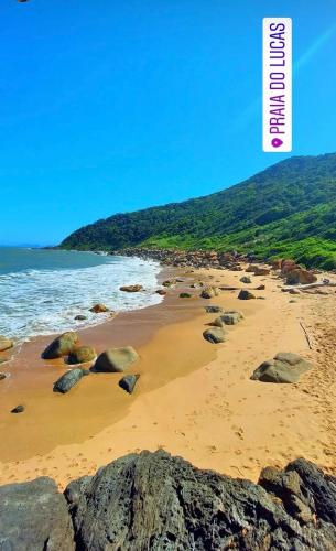 a sandy beach with rocks and the ocean at Chalés do Parque Hospedagem in Penha