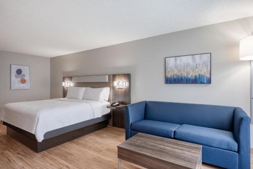 a hotel room with a bed and a blue couch at Holiday Inn Express Hotel & Suites Columbia-I-20 at Clemson Road by IHG in Columbia