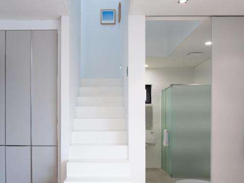 a white bathroom with a shower and a glass door at Boutique Pool Villa NAMIB in Jeju