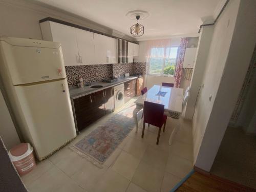 uma cozinha com uma mesa e um frigorífico branco em Spacious house near the airport em Arnavutköy