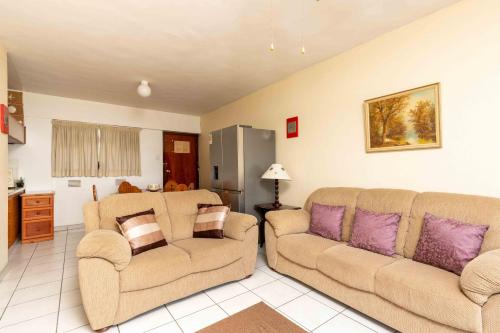 a living room with two couches and a kitchen at Amanzi402 Oceanview Retreat in Amanzimtoti