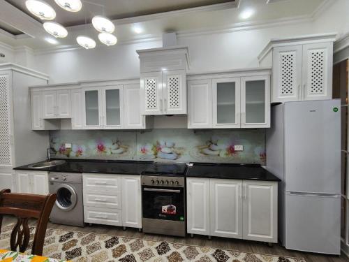 La cuisine est équipée de placards blancs et d'un réfrigérateur blanc. dans l'établissement Cozy apartment 2, à Samarcande