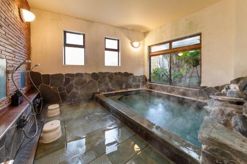 a large bath tub in a room with at 源泉かけ流しの露天風呂を独り占め！一棟貸切旅館「御宿あさか」29名まで宿泊可 in Ena