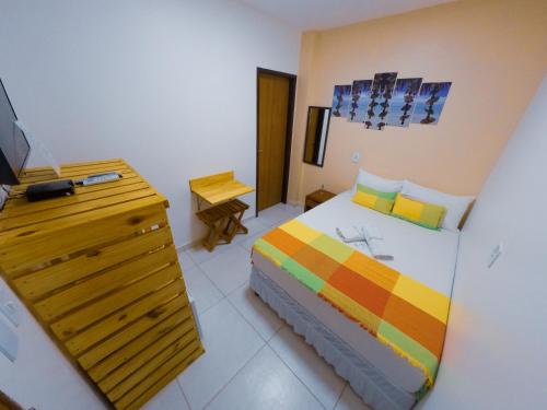 a bedroom with a bed and a dresser with a television at Barra Grande Pousada in Maragogi