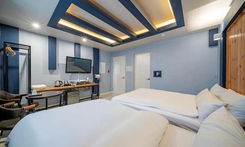 a bedroom with two beds and a desk and a television at 충주 호텔 발리 in Chungju