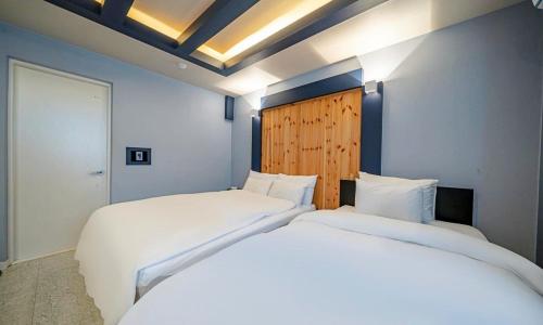 Chungju Bali Hotel في تشونغجو: سريرين بيض في غرفة بجدران زرقاء