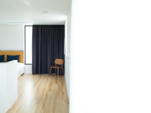 a hotel room with a bed and a chair at Boutique Pool Villa NAMIB in Jeju