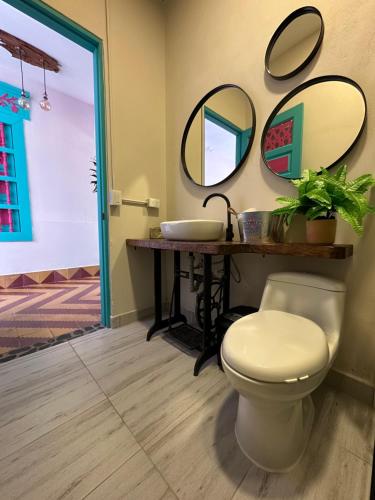 a bathroom with a toilet and mirrors on the wall at CASA HOTEL LAS HORTENSIAS in Jardin