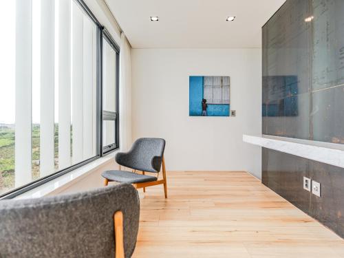 a room with a chair and a wall of windows at Boutique Pool Villa NAMIB in Jeju