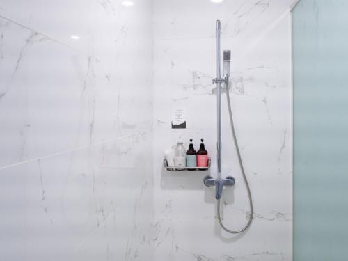 a white bathroom with a shower with bottles on a shelf at Boutique Pool Villa NAMIB in Jeju