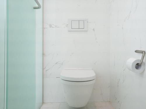 a white bathroom with a toilet and a roll of toilet paper at Boutique Pool Villa NAMIB in Jeju