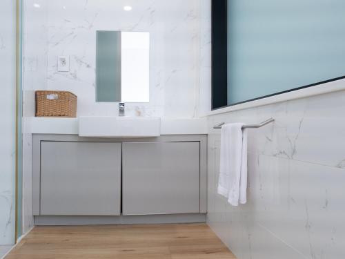 a white bathroom with a sink and a mirror at Boutique Pool Villa NAMIB in Jeju
