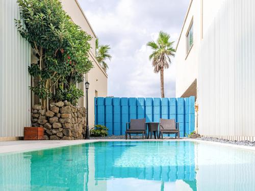 a swimming pool with two chairs and a table next to a building at Boutique Pool Villa NAMIB in Jeju